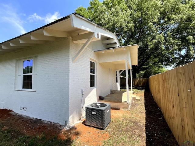 view of home's exterior featuring central air condition unit, crawl space, brick siding, and a fenced backyard