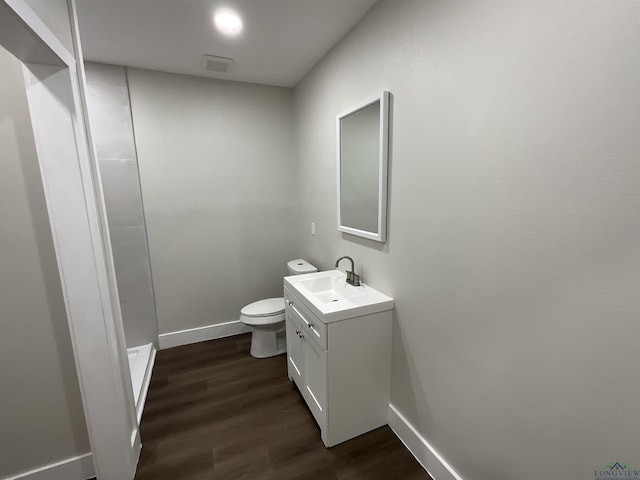 bathroom with a shower, baseboards, toilet, wood finished floors, and vanity