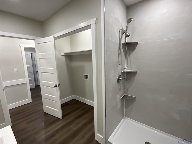 bathroom featuring wood finished floors, a tile shower, and baseboards