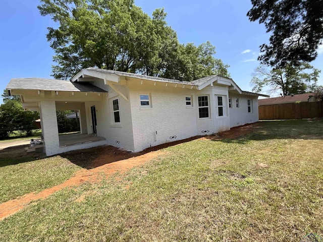 view of property exterior with a lawn, fence, a patio, and brick siding