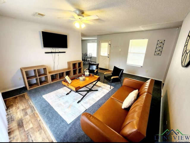 living room featuring ceiling fan, a textured ceiling, and hardwood / wood-style floors