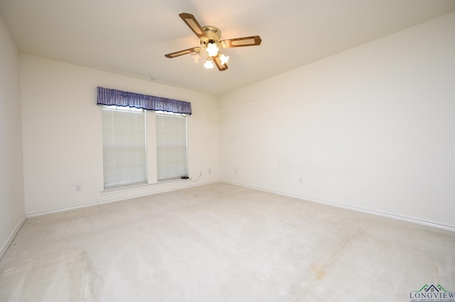 unfurnished room with baseboards, a ceiling fan, and light carpet