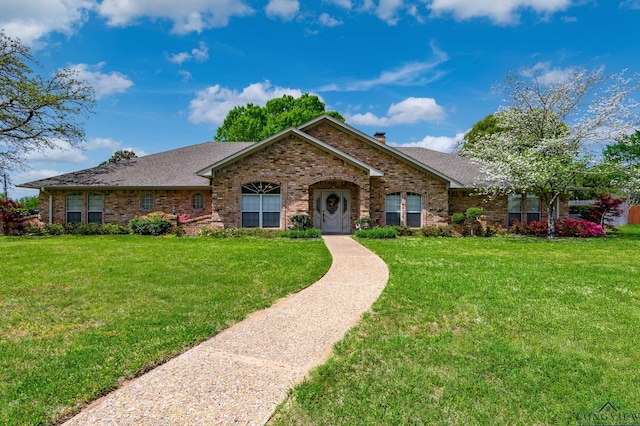 single story home with a front yard, a chimney, brick siding, and roof with shingles