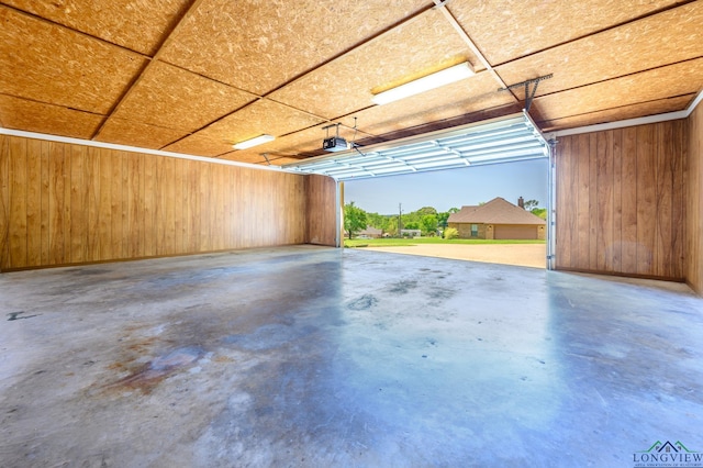 garage with a garage door opener and wood walls