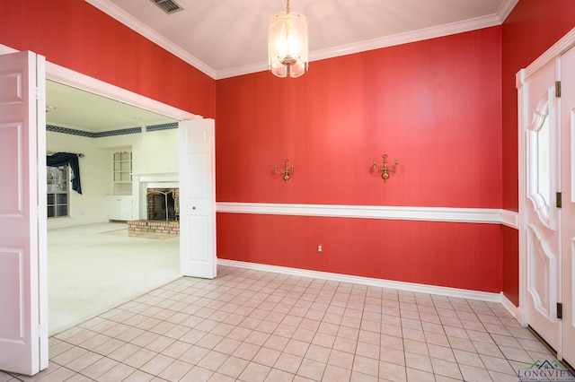 unfurnished room featuring tile patterned flooring, a brick fireplace, an inviting chandelier, and ornamental molding