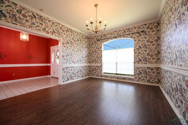 unfurnished room featuring a chandelier, wallpapered walls, wood finished floors, and ornamental molding