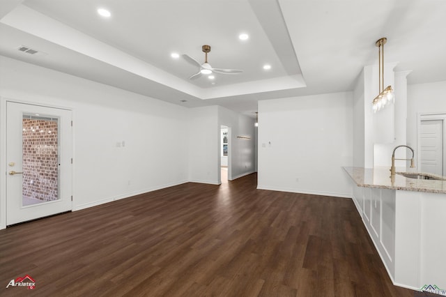 unfurnished living room featuring a tray ceiling, ceiling fan, sink, and dark hardwood / wood-style floors