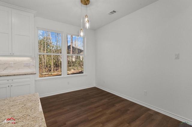 unfurnished dining area with dark wood-type flooring