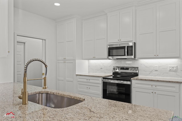 kitchen with white cabinets, stainless steel appliances, light stone countertops, and sink