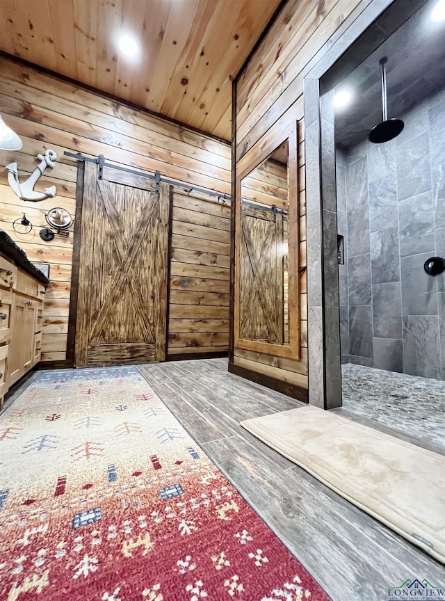 hall with wood walls, a barn door, and wooden ceiling