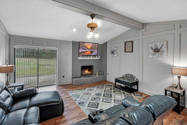 living room with hardwood / wood-style floors, a textured ceiling, vaulted ceiling with beams, and a fireplace