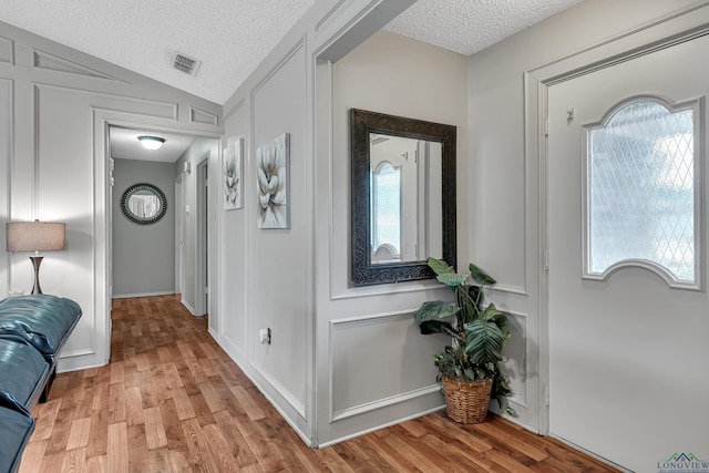 hall featuring plenty of natural light, a textured ceiling, and light wood-type flooring