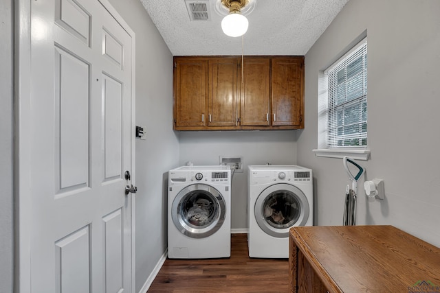 clothes washing area with cabinets, a textured ceiling, dark wood-type flooring, and washer and clothes dryer