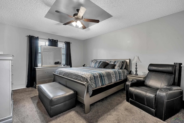 bedroom with a textured ceiling, carpet flooring, a tray ceiling, and ceiling fan