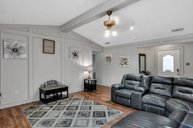 living room featuring wood-type flooring, lofted ceiling with beams, and a textured ceiling