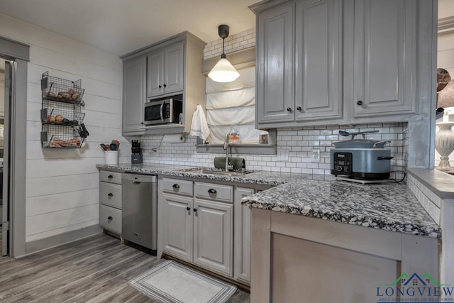 kitchen featuring a sink, decorative backsplash, appliances with stainless steel finishes, and gray cabinetry