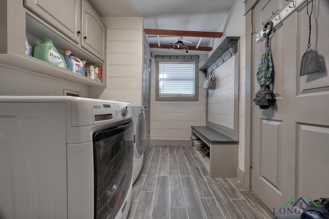 laundry area with cabinet space, separate washer and dryer, wood walls, and wood tiled floor