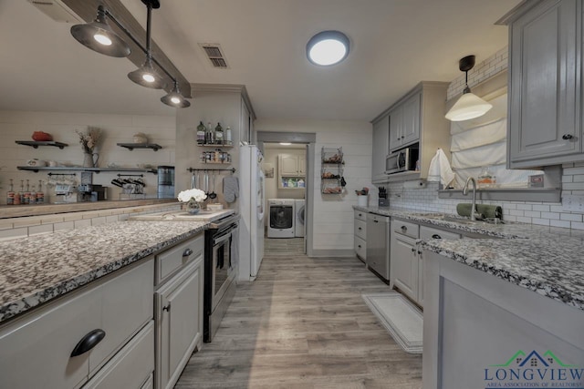 kitchen with open shelves, gray cabinets, appliances with stainless steel finishes, washer and dryer, and backsplash