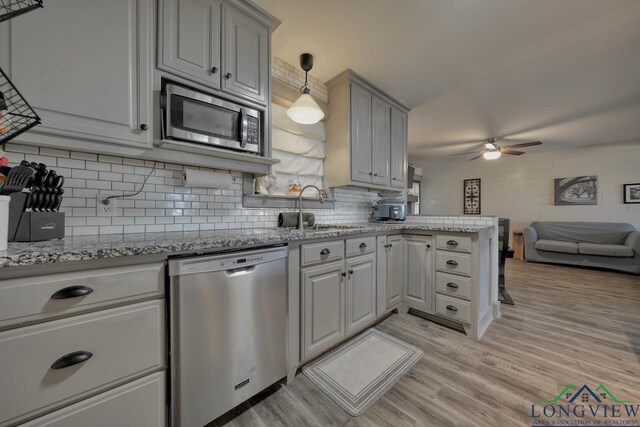 kitchen with a sink, stainless steel appliances, light wood-style floors, a peninsula, and ceiling fan