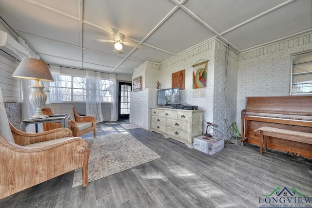 sitting room with brick wall, an AC wall unit, a ceiling fan, and wood finished floors