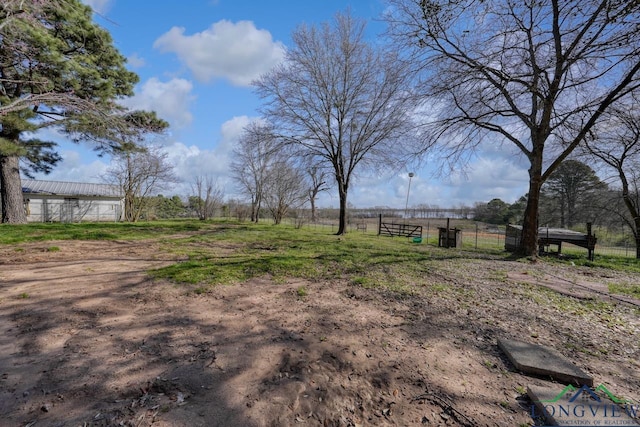 view of yard with a rural view, an outdoor structure, and fence