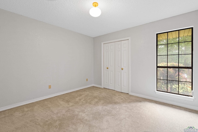 1307 Spring Tree Ln, Kilgore, TX 75662 - unfurnished bedroom featuring carpet floors, a textured ceiling, baseboards, and a closet