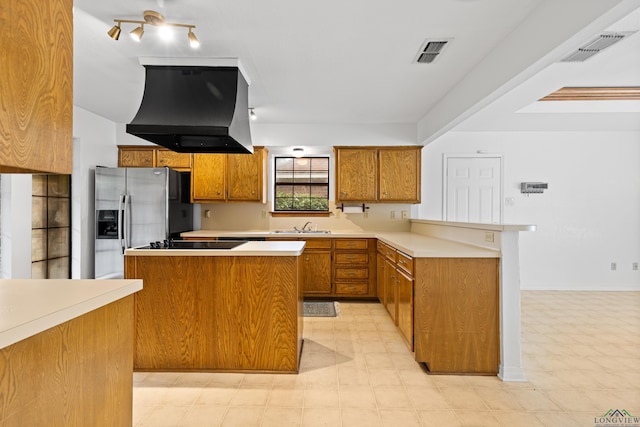 1307 Spring Tree Ln, Kilgore, TX 75662 - kitchen with custom exhaust hood, stainless steel fridge, brown cabinets, a sink, and a peninsula