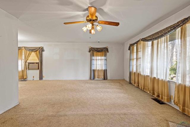 empty room featuring carpet flooring, ceiling fan, cooling unit, and a healthy amount of sunlight