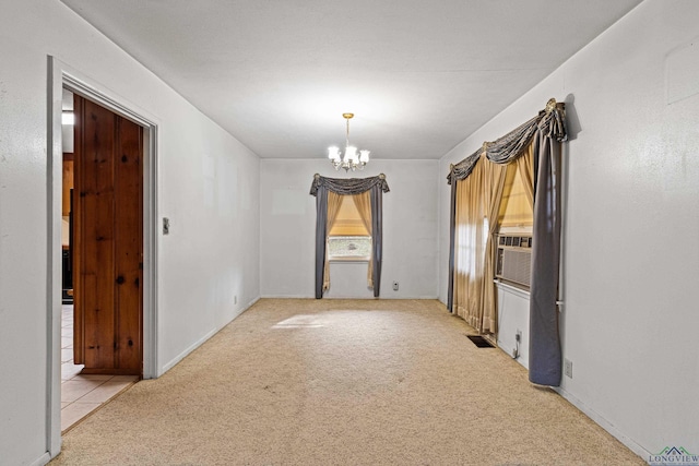 carpeted empty room featuring a notable chandelier