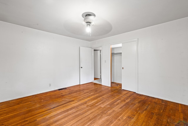 unfurnished bedroom featuring hardwood / wood-style floors, a closet, and ceiling fan