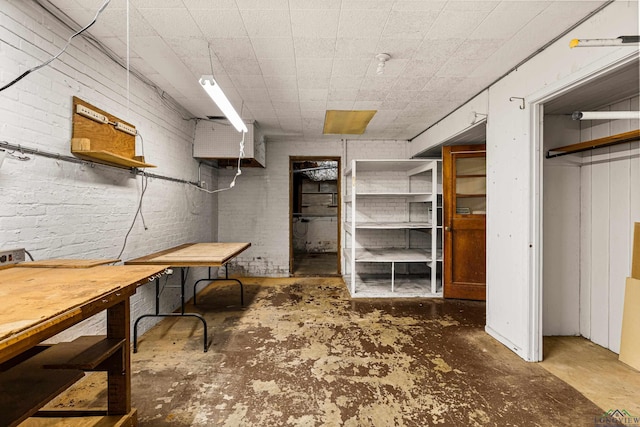 basement with a workshop area and brick wall