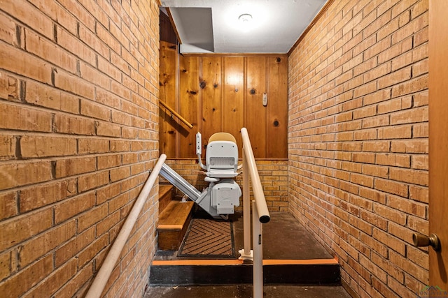 stairway featuring wood walls and brick wall