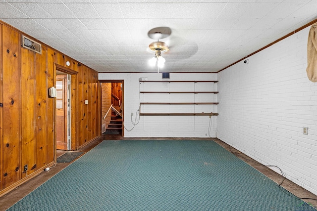 unfurnished room featuring wooden walls and brick wall