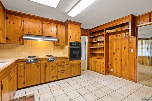 kitchen featuring gas stovetop, black oven, tasteful backsplash, and light tile patterned flooring