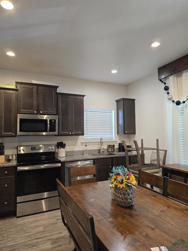 203 W Gay Ave, Gladewater, TX 75647 - kitchen with stainless steel appliances, a sink, light wood-style floors, dark brown cabinetry, and recessed lighting