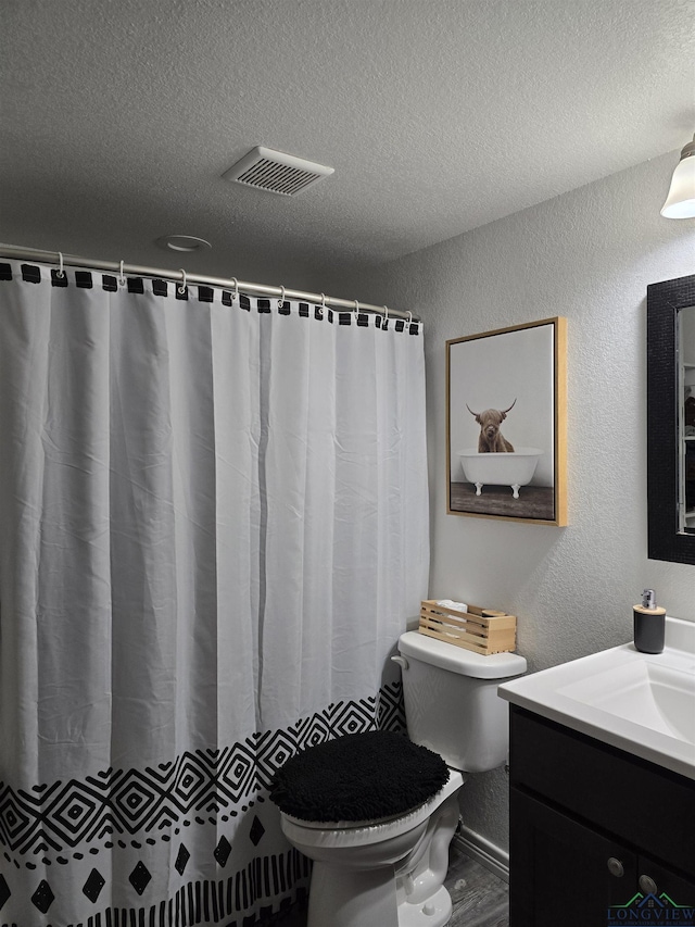 203 W Gay Ave, Gladewater, TX 75647 - bathroom with vanity, toilet, a textured ceiling, a textured wall, and a shower with curtain