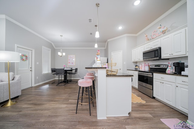 kitchen featuring a center island with sink, a kitchen breakfast bar, tasteful backsplash, white cabinetry, and stainless steel appliances