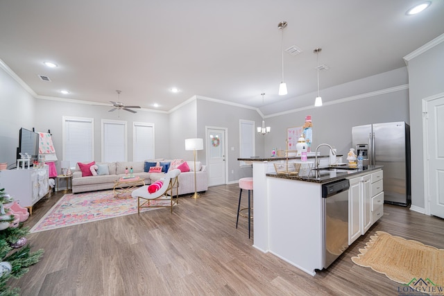 kitchen featuring an island with sink, pendant lighting, a kitchen bar, white cabinets, and appliances with stainless steel finishes