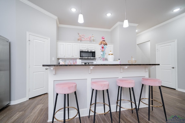 kitchen with white cabinets, dark hardwood / wood-style flooring, a kitchen bar, and ornamental molding