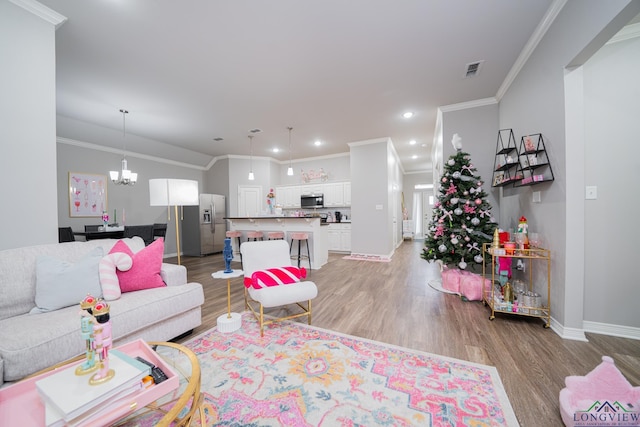 living room featuring crown molding, light hardwood / wood-style flooring, and a chandelier