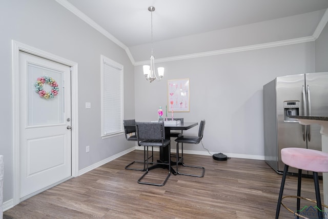 dining area featuring hardwood / wood-style floors, a notable chandelier, crown molding, and vaulted ceiling