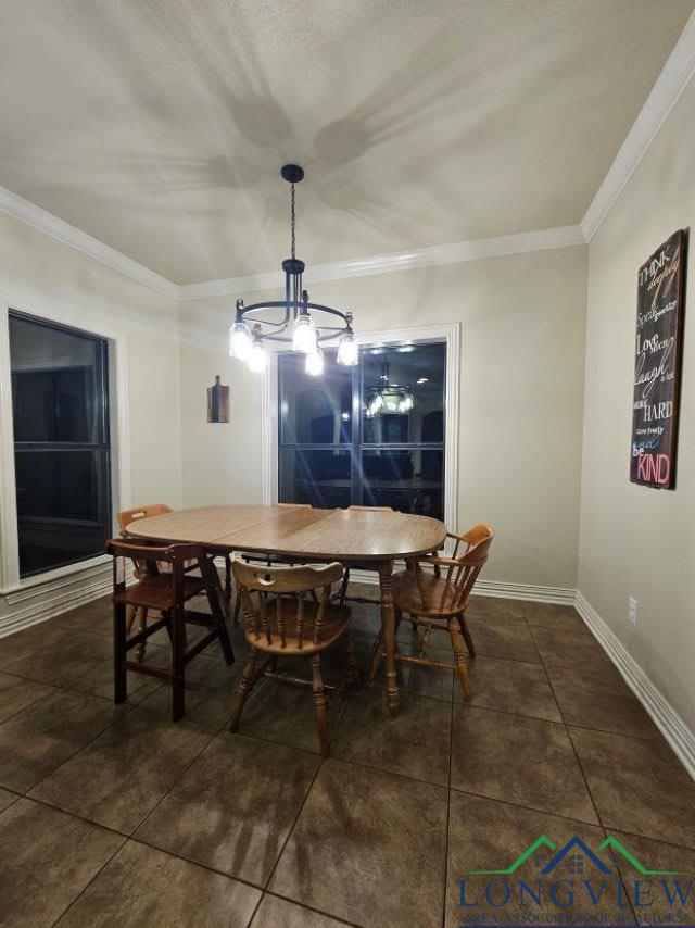240 Cedar Ridge Rd, Longview, TX 75602 - dining area with ornamental molding, a chandelier, dark tile patterned floors, and baseboards