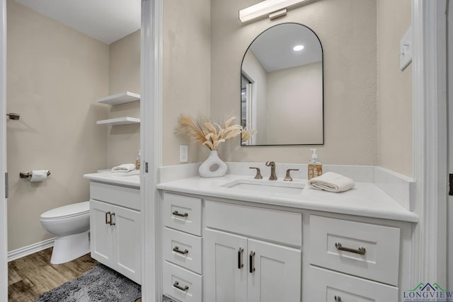 bathroom featuring toilet, vanity, and hardwood / wood-style flooring