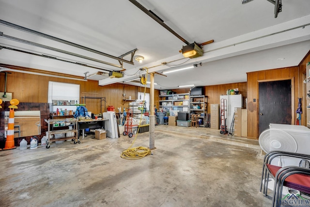 garage featuring a workshop area, wood walls, a garage door opener, and white refrigerator