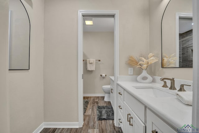 bathroom with vanity, toilet, and wood-type flooring