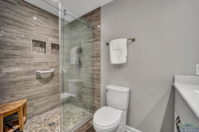 bathroom with an enclosed shower, vanity, and toilet