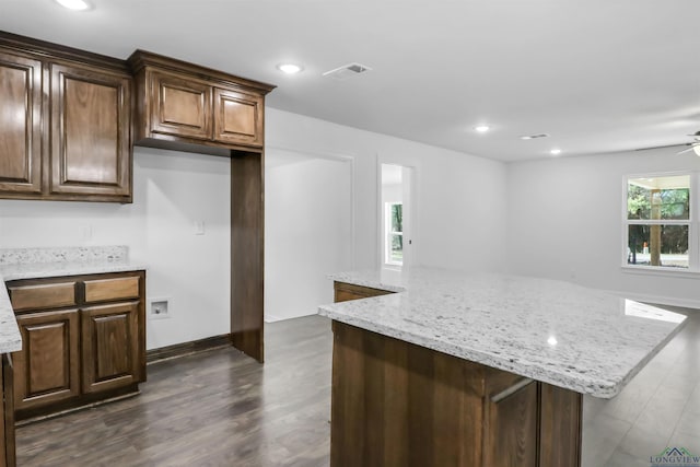 kitchen featuring light stone countertops, a kitchen island, a wealth of natural light, and ceiling fan