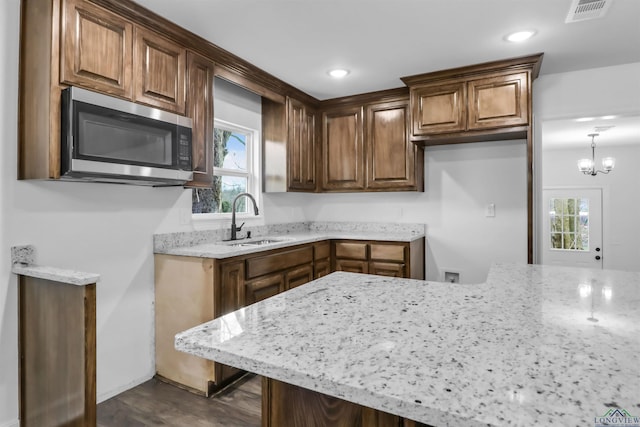 kitchen featuring dark hardwood / wood-style flooring, light stone counters, sink, an inviting chandelier, and hanging light fixtures