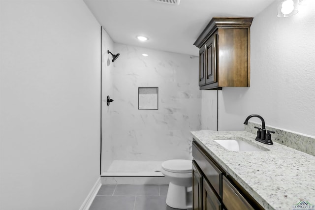 bathroom with tile patterned flooring, a tile shower, vanity, and toilet