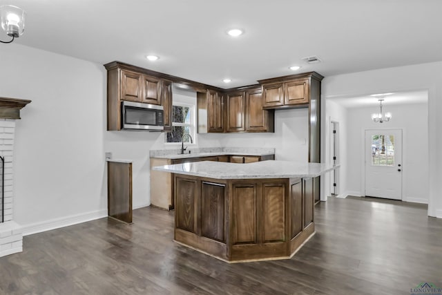 kitchen featuring sink, dark hardwood / wood-style flooring, a notable chandelier, pendant lighting, and a kitchen island